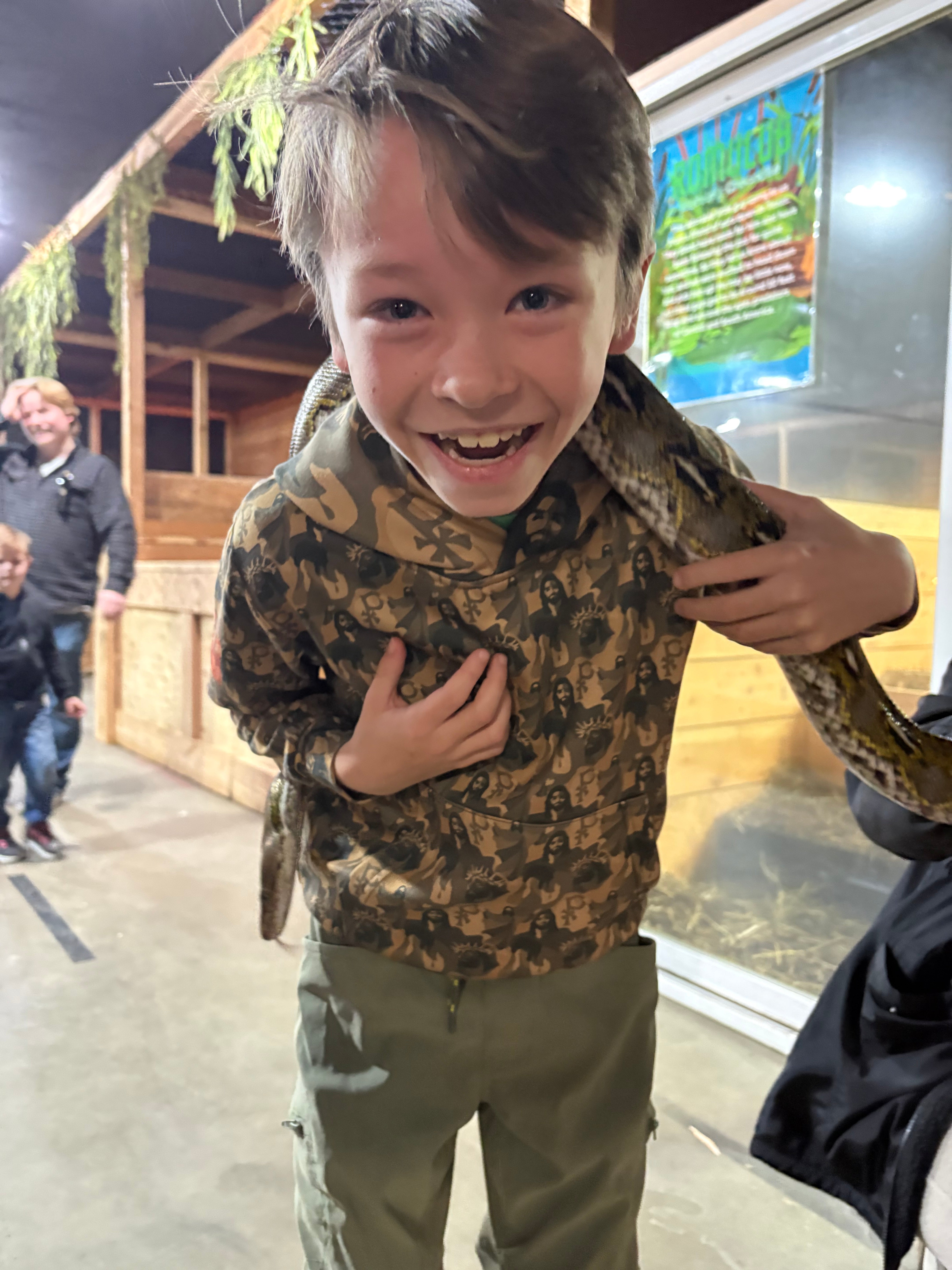 Child with a jesus camo christian hoodie holding a snake with a blurred background