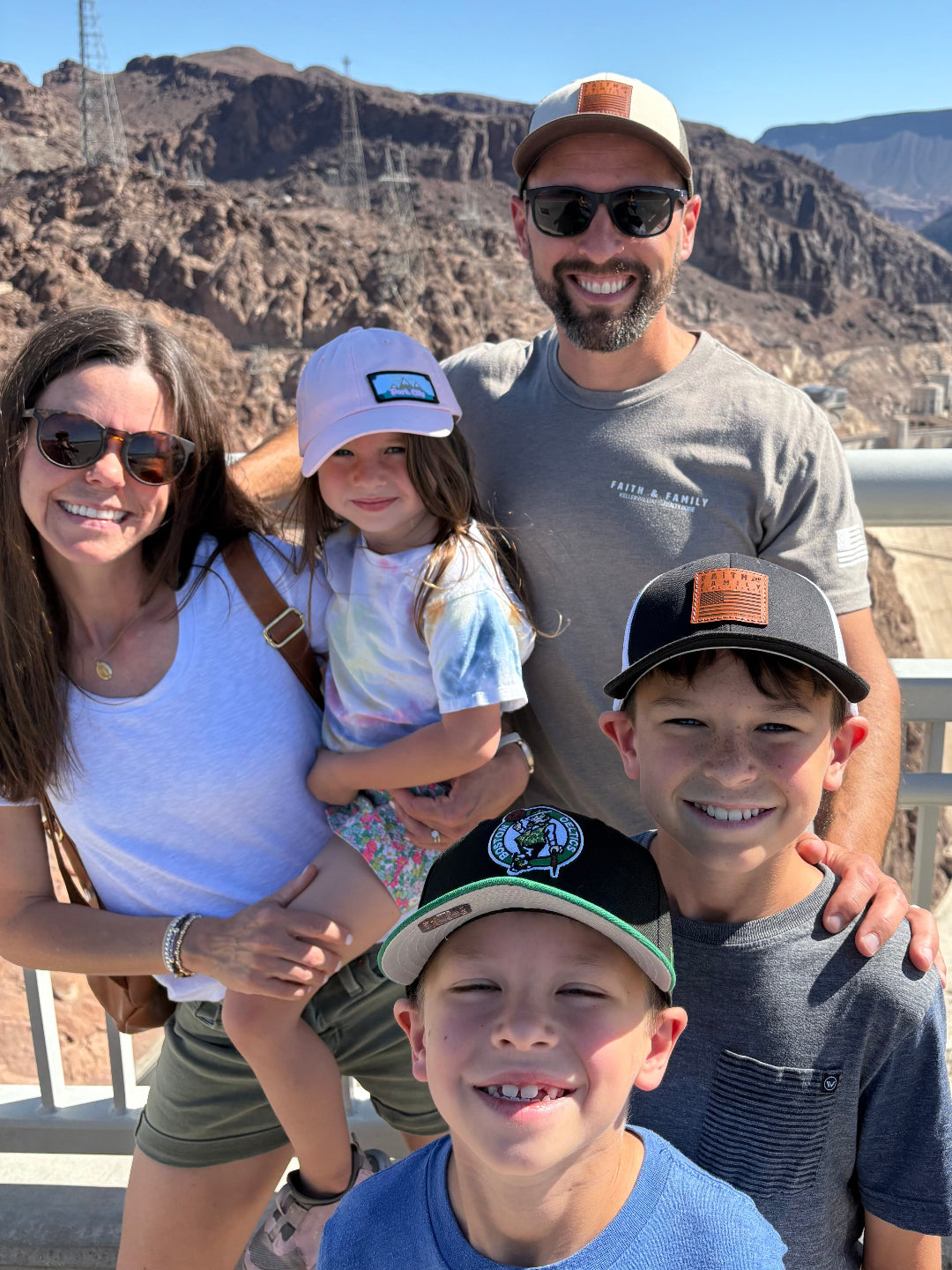 Family of five posing for a photo with mountains in the background