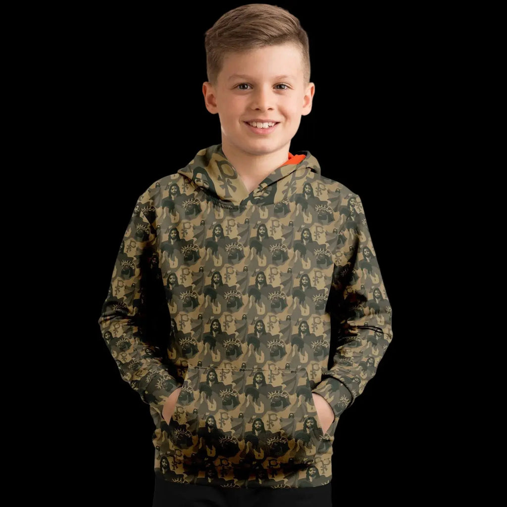 Mockup view of the front of a kids hoodie with a jesus camouflage pattern worn by a boy against a black background