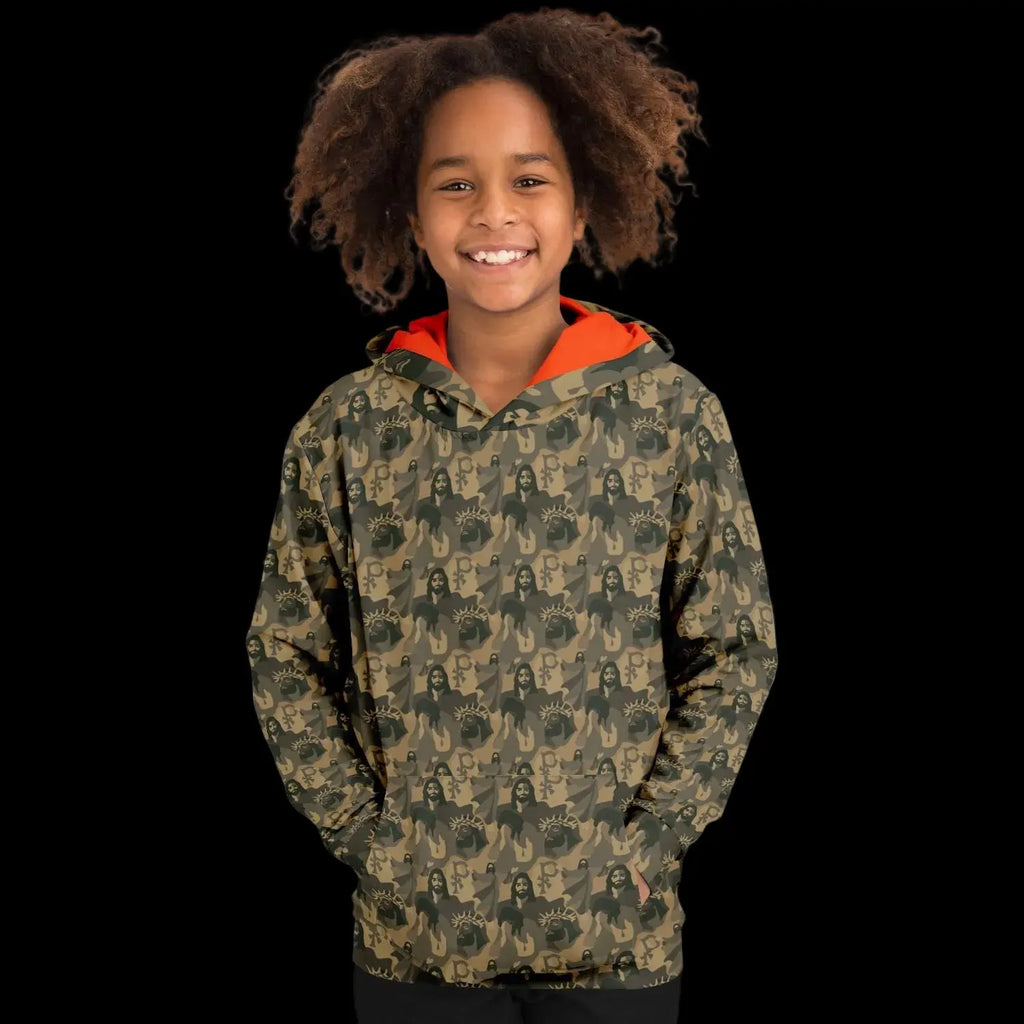 Mockup view of the front of a kids hoodie with a jesus camouflage pattern worn by a girl against a black background
